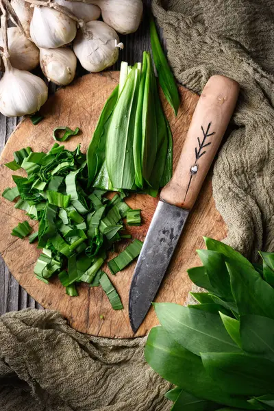 用小刀在木板上切碎新鲜的有机熊野大蒜叶 食品摄影 图库照片