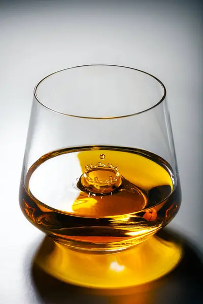 一杯威士忌 里面滴着一滴水花 奢侈酒的概念 免版税图库照片
