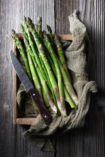 新鲜的芦笋芽插在木箱里 配有小刀和厨房地毯 顶部视图 食品摄影 图库图片