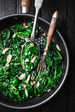 Kızartma tavasında lezzetli ıspanak, sarımsak ve fındık. Sağlıklı vejetaryen yemekleri. en üstteki görünüm