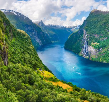 Norveç 'in batısındaki Geiranger köyü yakınlarında Sunnylvsfjorden fiyordunun berrak gök mavisi suları ve ünlü Seven Sisters şelaleleri inanılmaz görünüyor.
