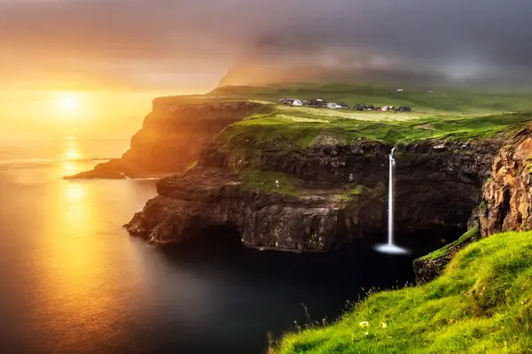 Stock image Mulafossur waterfall on sunset time. Dramatic sky with golden light. Gasadalur village, Vagar Island, Faroe Islands, Denmark. Landscape photography