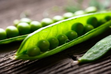 Tahta üzerinde yeşil bezelye tanecikleri. Yeşil bezelye fasulyesi sebzeleri yakın. Yemek fotoğrafçılığı