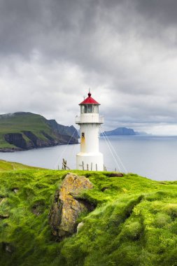 Danimarka 'nın Faroe Adaları' ndaki Mykines Adası 'nın yemyeşil tepelerindeki Mykines Holmur Deniz Feneri' nin inanılmaz manzarası. Peyzaj fotoğrafçılığı
