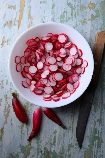 Turp salatası hazırlığı. Tahta bir tabakta bıçakla ince turp dilimleri. Yemek fotoğrafçılığı