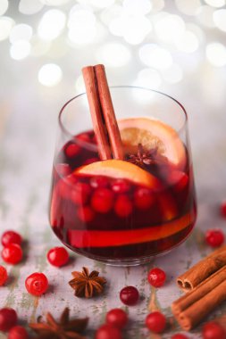 Noel içeceği - kırmızı baharatlı sıcak şarap bardakta Noel ışıkları ve kızılcık yakından.