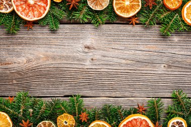 Yeşil köknar dalları, kurutulmuş turunçgiller, portakal dilimleri ve anis yıldızlarından oluşan bir Noel veya Yeni Yıl arkaplanı. Rustik Ahşap Süs Arkaplanı