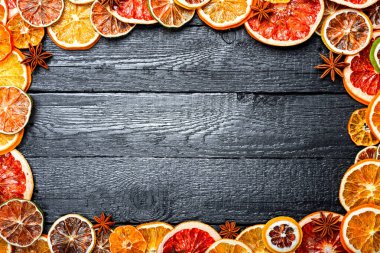 Noel ya da yeni yıl arkaplanı, eski siyah ahşap tahta ve kurumuş narenciye dilimleri ve anis yıldızlarının sınırı. Rustik Ahşap Süs Arkaplanı