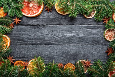 Yeşil köknar dalları, kurutulmuş turunçgiller, portakal dilimleri ve anis yıldızlarından oluşan bir Noel veya Yeni Yıl arkaplanı. Rustik Ahşap Süs Arkaplanı