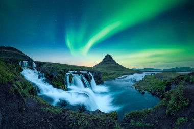 Kirkjufellsfoss şelalesinin panoramik manzarası Kuzey ışıklarıyla inanılmaz bir gökyüzü altında. İzlanda 'da Kirkjufell Volkano ve kutup ışıklarıyla muhteşem bir manzara. Aurora borealis