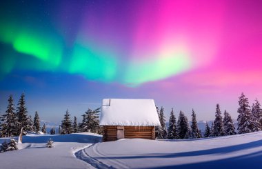 Karlı ormandaki ahşap kulübenin üzerinde mor kuzey ışığı olan bir Noel manzarası. Donmuş dağlarda kutup ışıklarıyla geçen kış sahnesi. Aurora Borealis