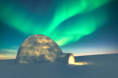 Snowy igloo lighted from the inside against the backdrop of incredible starry sky with green waves of Aurora borealis. Polar lights. Northern lights in winter field. clipart