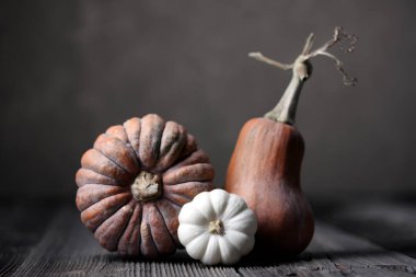 Tahta masada üç farklı balkabağı. Koyu kahverengi arka plan. Yakın plan.