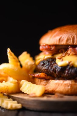 Tahta tahtada patates kızartması ve iştah açıcı çizburger. Yemek fotoğrafçılığı. Makro çekim