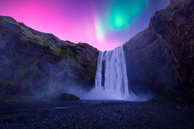 Aurora Borealis over famous Skogafoss waterfall on Skoga river, Iceland. Gorgeous Icelandic landscape with waterfall and Northern lights. Polar lights clipart