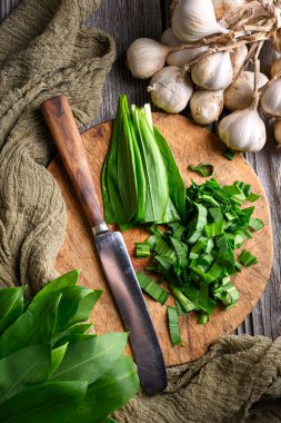 Tahta tahtada yabani sarımsak yapraklarını bıçakla kesiyor. Yemek fotoğrafçılığı