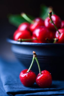 Mavi bir masa örtüsü üzerinde olgun taze kırmızı kirazlar. Yemek fotoğrafçılığı