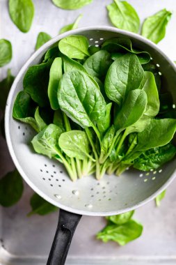 Metal kevgire sarılmış taze ıspanak yaprakları. Çiğ organik bebek ıspanağı.