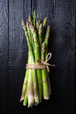 Siyah ahşap masada taze kuşkonmaz filizleri. Üst Manzara. Yemek fotoğrafçılığı