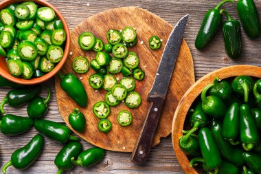 Tahta kesme tahtasının üzerinde bıçakla dilimlenmiş yeşil jalapeno. Acı Meksika biberi hazırlıkları. Yemek fotoğrafçılığı