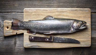 Kuzey Kutbu şamandırası balığıyla ahşap tahta kesme tahtası kırsal masada. Tatlı su nehri alabalığı yaklaşıyor. Yemek fotoğrafçılığı