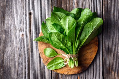 Yeşil ıspanak yapraklarının kırsal ahşap masa üzerinde su damlaları. Organik ıspanak yeşillikleri. Yemek fotoğrafçılığı