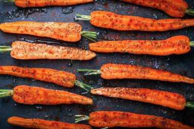 Fırında pişirmek için hazırlanmış havuç manzarası. Baharatlı kızarmış havuç yarımları.