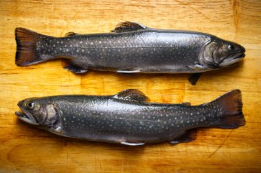 Kırsal kesim tahtasındaki iki kutup balığının üst görüntüsü. Tatlı su nehri alabalığı yaklaşıyor. Yemek fotoğrafçılığı