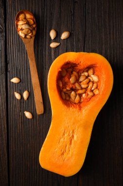 Tahta kaşık ve tahta masa manzaralı çiğ tereyağlı kabak. Balkabağının yarısı yakın plan. Yemek fotoğrafçılığı