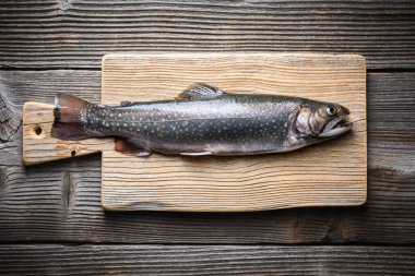 Köy masasında tahta kesme tahtasında taze balık. Tatlı su nehri alabalığı yaklaşıyor. Yemek fotoğrafçılığı