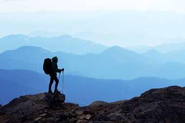 Sırt çantalı bir turistin silüeti yüksek karlı dağların arka planında. Seyahat ve macera konsepti