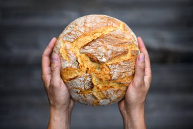 Fırıncıların ellerini geleneksel mayalanmış ekşi ekmekle kırsal ahşap masa arkaplanında kapatın. Sağlıklı yemek fotoğrafçılığı