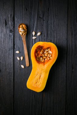 Ahşap kaşık ve kırsal ahşap masada tohum bulunan yarım yamalak tereyağlı kabak manzarası. Sonbahar mutfağı mevsimlik yemek ya da sonbahar yemeği hazırlamak için yatıyordu.