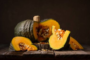 Yeşil balkabağı, içerideki portakalı mutfak bıçağıyla ortaya çıkarmak için kesilmiş. Sonbahar sebzeleri ve bayram yemeği hazırlama mevsimsel gıda konsepti