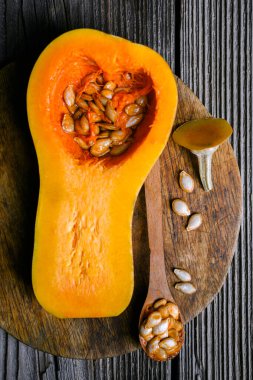 Tahta kesme tahtasının üzerinde tahta kaşık ve tohumlarla tereyağlı ezme. Genel sonbahar sahnesi yemek içeriği ya da mevsimlik yemek fotoğrafçılığı için ideal