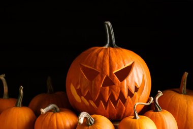 Yüzü oyulmuş balkabağı ve turuncu mini kaplı Cadılar Bayramı kompozisyonu. Ürkütücü mevsimlik dekorlar Sonbahar tatilleri ve karamsar kutlamalar için