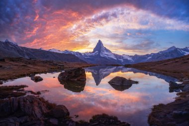 Dramatik ışık, Stellisee ve Matterhorn 'u İsviçre günbatımında canlı renklerle resmeder. Iconic Cervino zirvesi Zermatt 'ın yukarısındaki sakin alp gölünde yansıtılır.