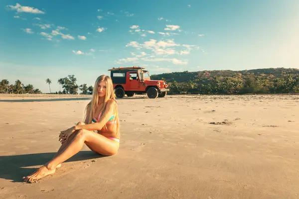 Блондинка Сидит Песчаном Пляже Красным Внедорожником Заднем Плане Пляж Стоковое Изображение