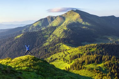 Man is standing on the lawn. Famous tourist destination with high mountains. Summer morning. Wallpaper background.