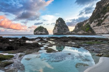 Turkuaz okyanus ve dağlar. Gün batımı manzarası. Diamond Sahili, Nusa Penida, Bali Adası, Endonezya. Duvar kağıdı arka planı. Doğal bir manzara. Romantik rahatlama yeri.