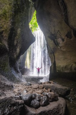 Elleri havada bir adam. Tukad Cepung Şelalesi Endonezya 'daki Ubud ormanında. Duvar kağıdı arka planı. Doğal bir manzara. Turistik tatil beldesi.