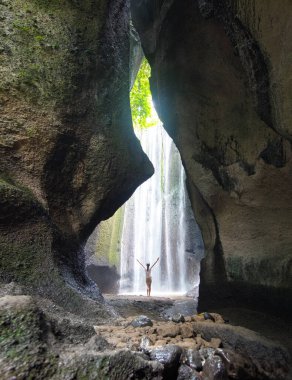 Tukad Cepung Şelalesi Endonezya 'daki Ubud ormanında. Elleri havada bir kız. Duvar kağıdı arka planı. Doğal bir manzara. Turistik tatil beldesi.