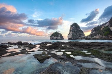 Scenery of sunny day with sand beach, turquoise ocean, blue sky, waves and mountains. View of Diamond beach, Nusa Penida, Bali island, Indonesia. Wallpaper background. Natural scenery.