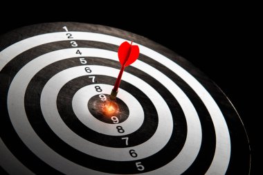 A red dart in the middle of a target board with a black background. The concept of setting goals for business success. with copy space for text.