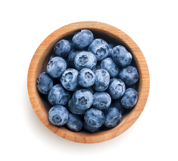 Ripe blueberries in a wooden plate close-up on a white background. Top view