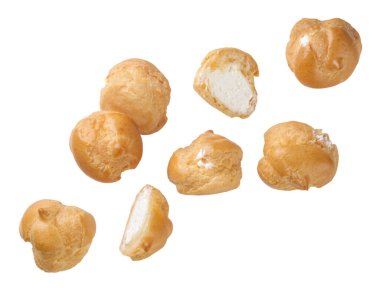 Profiterol ve yarımlar beyaz arka planda yakın planda uçarlar. İzole edilmiş