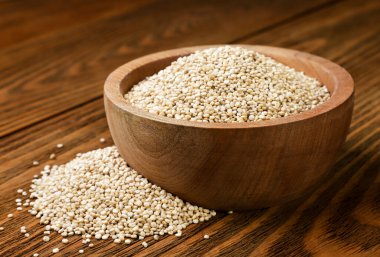 Bir tabakta kinoa var ve ahşap bir masaya yakın plan serpiştirilmiş. Süper yemek.