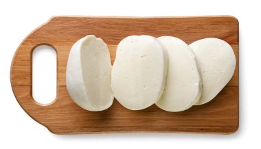 Mozzarella topu beyaz bir arka planda mutfak tahtasının üzerinde parçalara ayrılmış. Üst görünüm