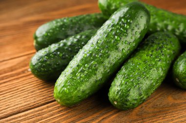 Tahta zemin üzerinde su damlacıkları olan taze salatalıklar..