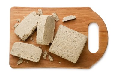 Halva ve parçalar tahta bir tahta üzerinde beyaz bir arka planda yakın plan. Üst görünüm